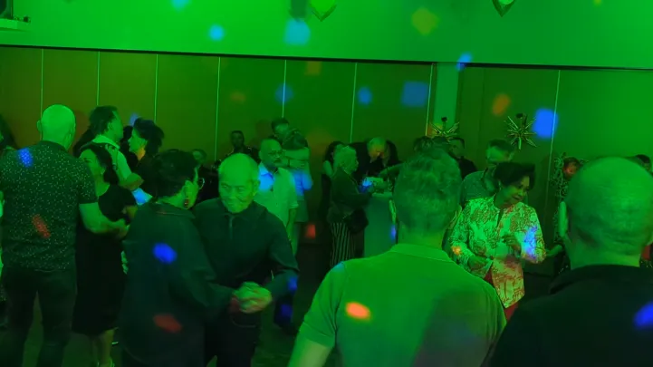 Gasten dansen gezellig samen op de dansvloer onder felgroene discoverlichting van Crazy4Sound tijdens een feest in Buurtcentrum Limbrichterveld, Geleen